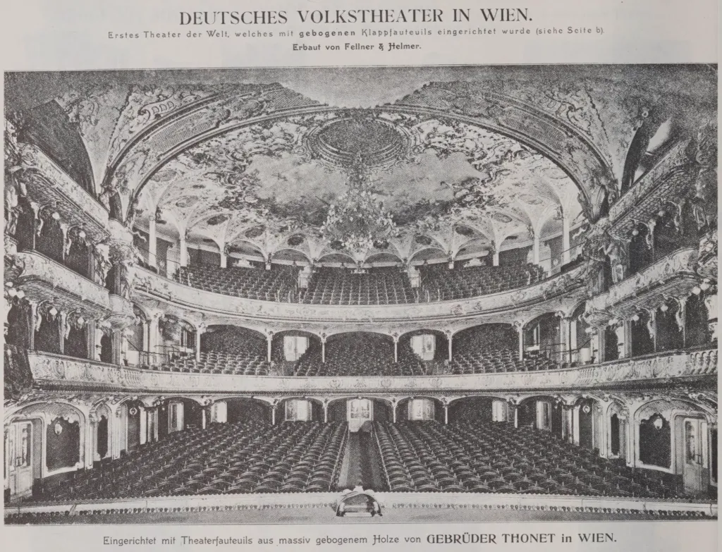 Historische Schwarz-Weiß-Aufnahme des prunkvollen Innenraums des Deutschen Volkstheaters in Wien mit Reihen von klappbaren Bugholz-Theaterfauteuils der Gebrüder Thonet, 1888.