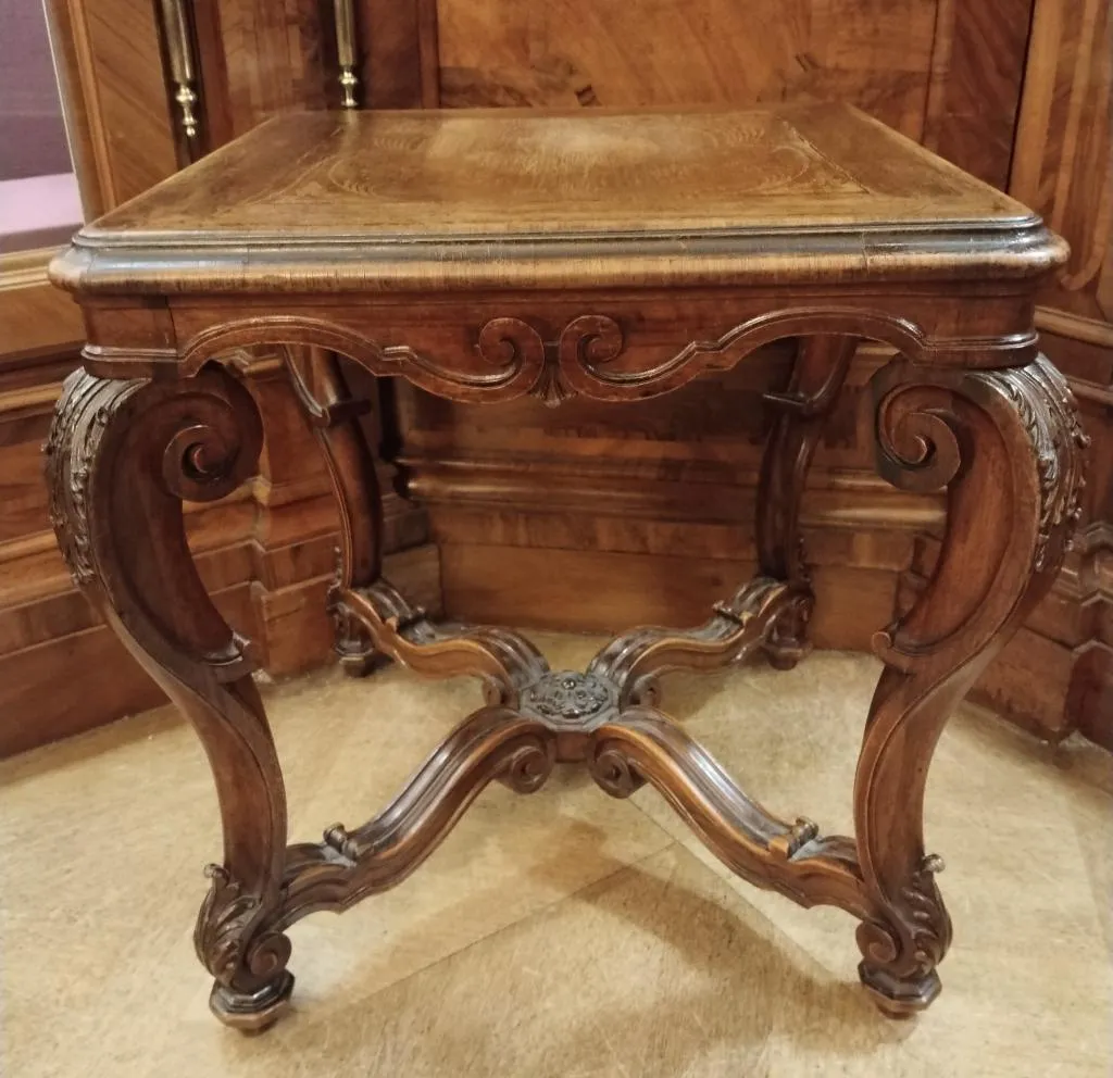 Antique wooden Chippendale-style stool from circa 1900 with carved legs and ornate stretcher.