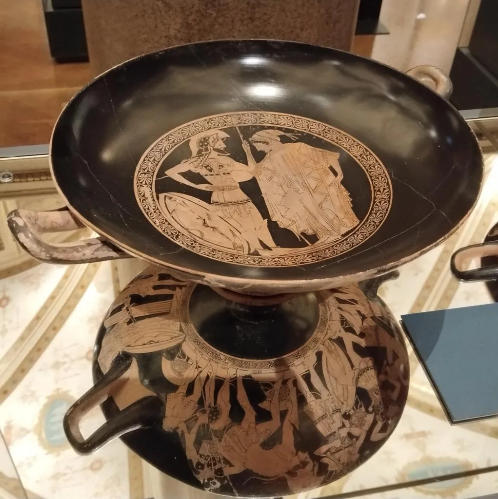 Ancient Attic red-figure kylix showing a bearded warrior with a woman offering a parting libation; outer scenes with warriors arming themselves, attributed to Duris, around 500 BC.