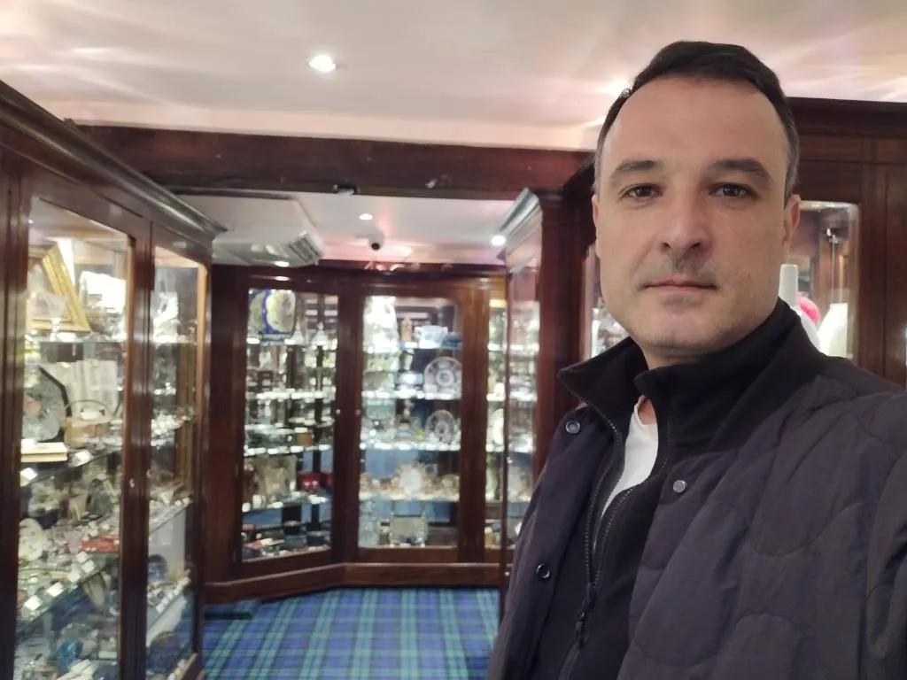 Exploring the interior of Cromwell’s Antique Centre - rows of gleaming cabinets showcase carefully curated antiques under warm lighting and original wooden beams.