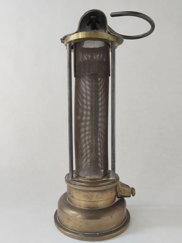Brass Davy safety lamp made by E. Thomas & Williams Ltd., showing protective wire gauze cylinder and support bars, designed for safe use in flammable mining environments.