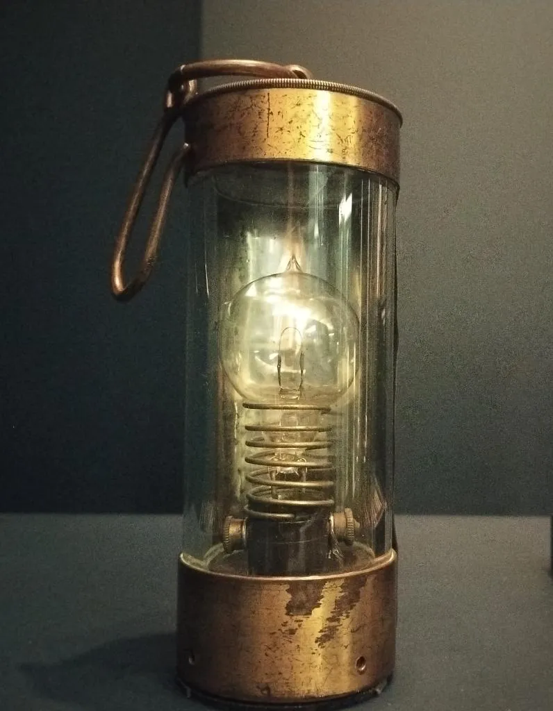 Photograph of a portable electric lamp from around 1880, featuring a Swan incandescent bulb and battery, produced by Swan United Electric Light Company, London. Displayed at the Vienna Technical Museum.