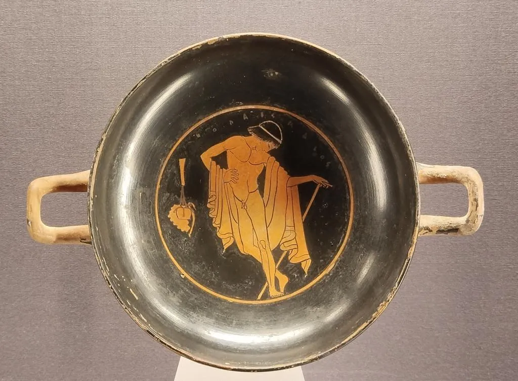 Antike griechische rotfigurige Schale mit Darstellung eines nackten Knaben, der sich in einer Palästra-Szene auf einen Stab stützt, um 490–480 v. Chr.