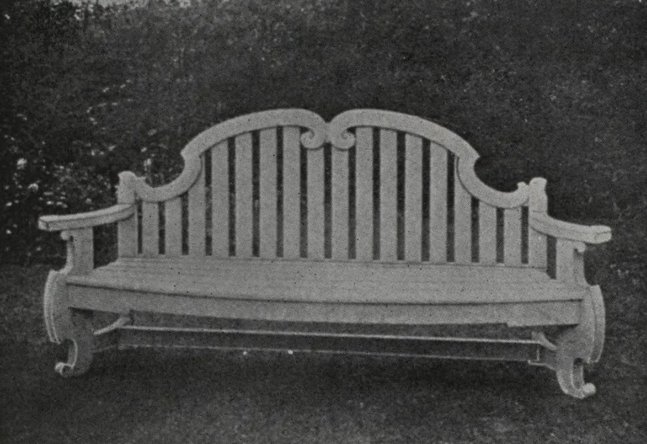 Black-and-white catalog photograph of a wooden garden bench featuring a distinctive double-scroll crest rail, vertical back slats, rolled arm supports, and curved legs in a refined French-inspired design.