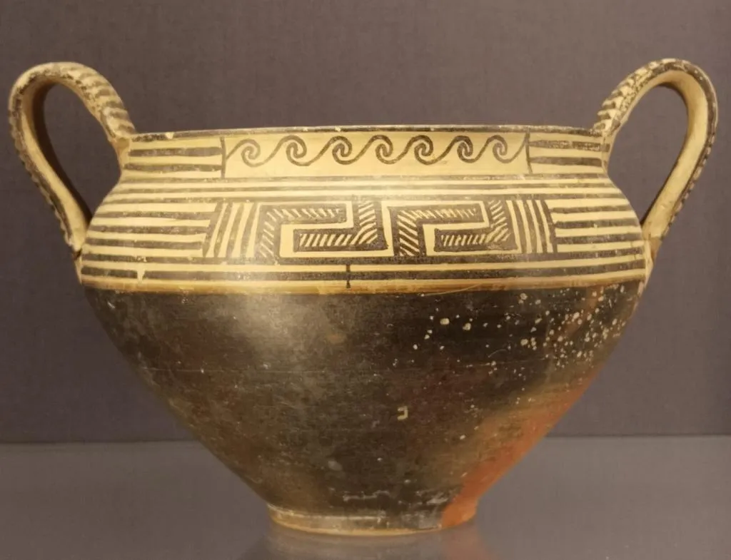 Early Greek Protocorinthian kantharos from around 700 BC with horizontal lines and a bold meander motif.