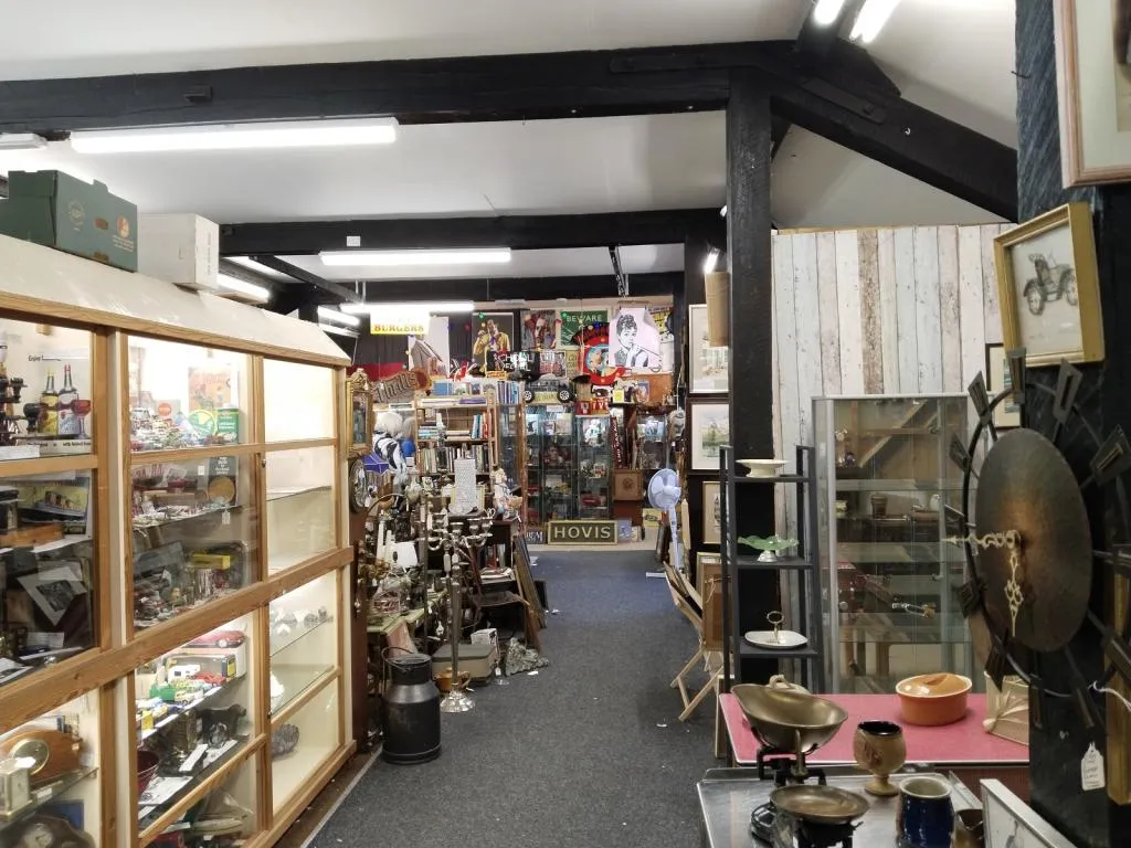 Another view of the main floor at Riverside Antiques Centre, showcasing a mix of display cabinets, vintage signage, collectibles, and eclectic dealer setups.