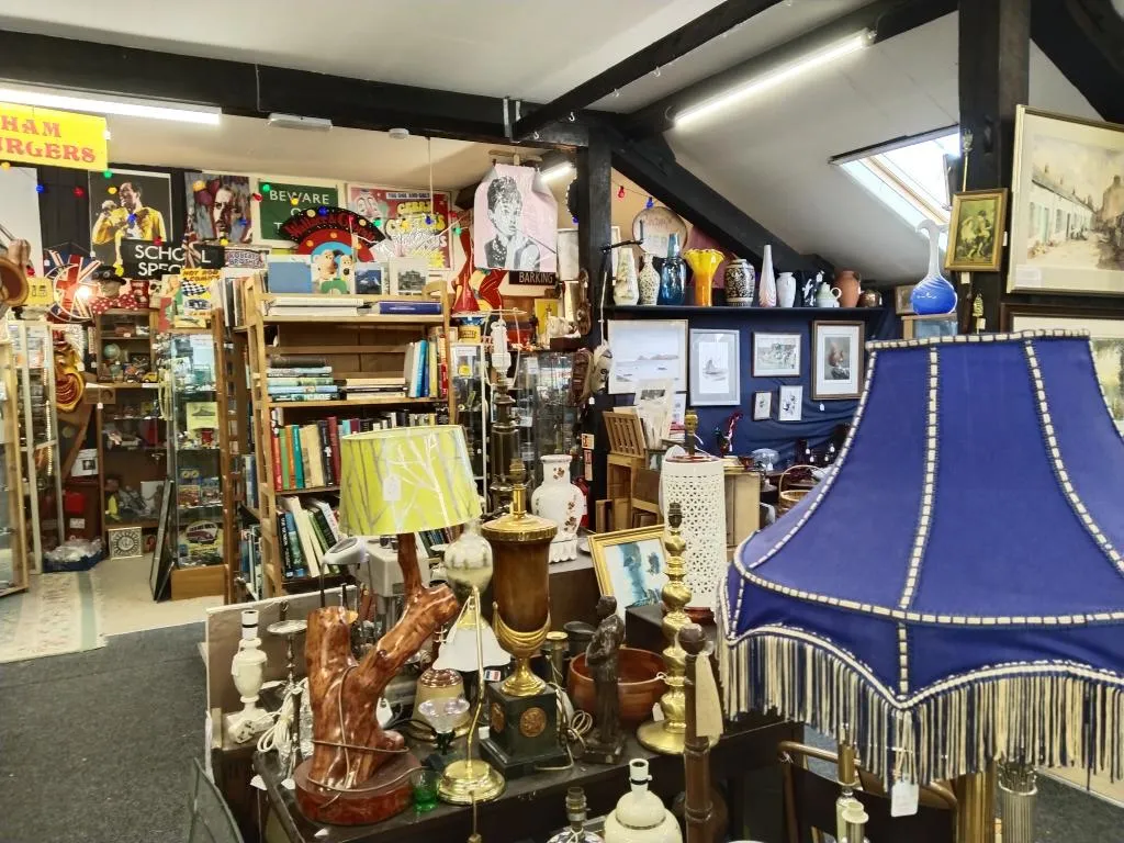 Eclectic mix of vintage lamps, books, and decorative art—typical of Riverside Antiques’ densely packed dealer setups.