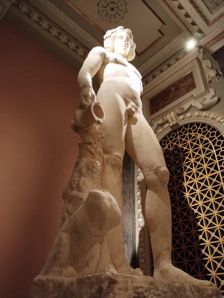 Römische Marmorstatue des Dionysos-Bacchus, 2. Jahrhundert n. Chr., nackt stehend mit Kantharos in der rechten Hand (ein Henkel fehlt), von Rebe und Tier begleitet.