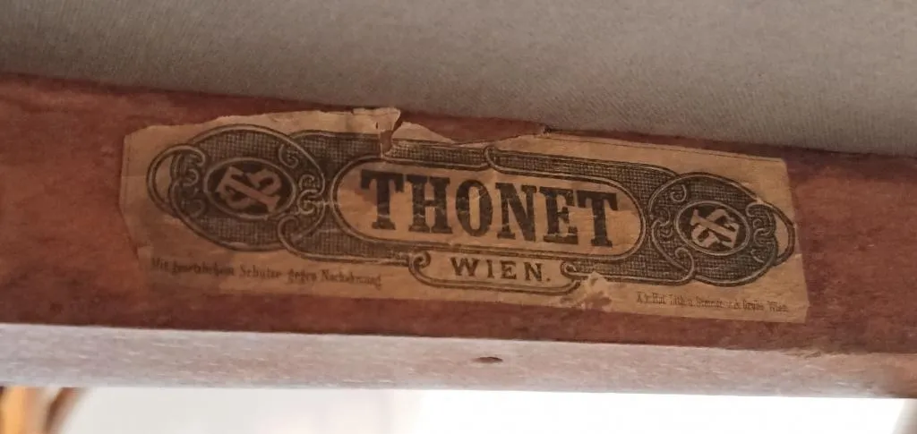 Nahaufnahme eines späteren Thonet-Papieretiketts auf einem Holzrahmen, mit der schwarzen Aufschrift THONET WIEN und dekorativem Rahmen.