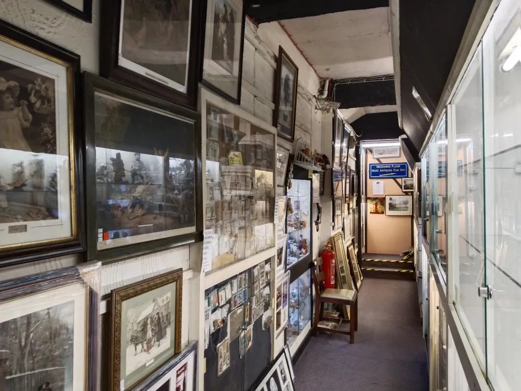 Corridor wall lined with framed prints, postcards, and sports memorabilia.