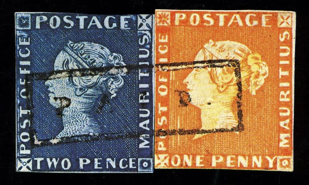 Die berühmten roten und blauen Mauritius-Briefmarken. Die linke Briefmarke ist blau und zeigt das Profil einer Frau mit der Aufschrift „POSTAGE“ oben, „MAURITIUS“ rechts und „TWO PENCE“ unten. Die rechte Briefmarke ist rot und zeigt dasselbe Profil einer Frau mit der Aufschrift „POSTAGE“ oben, „MAURITIUS“ rechts und „ONE PENNY“ unten. Beide Briefmarken haben schwarze Stempelmarkierungen und weisen Alters- und Gebrauchsspuren auf, die ihren historischen Wert unterstreichen.