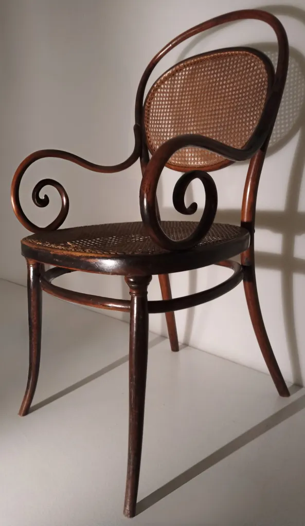 Side view of Thonet bentwood armchair Model No. 11, showing rounded cane backrest, curved support ring beneath the seat, and prominent spiral armrests.