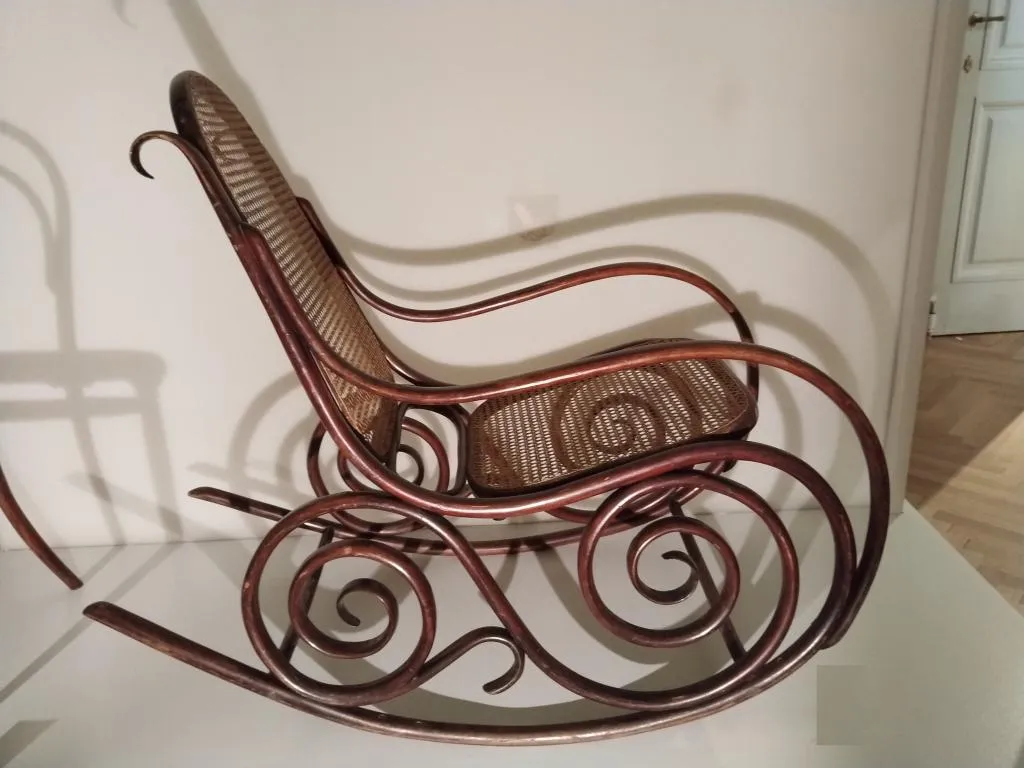 Thonet Schaukelfauteuil Modell Nr. 9, um 1890 von den Gebrüdern Thonet gefertigt. Aus massiv gebogenem, braun gebeiztem Buchenholz mit Sitz- und Rückenfläche aus Rohrgeflecht, verziert mit eleganten Spiralen an den Seitenteilen.