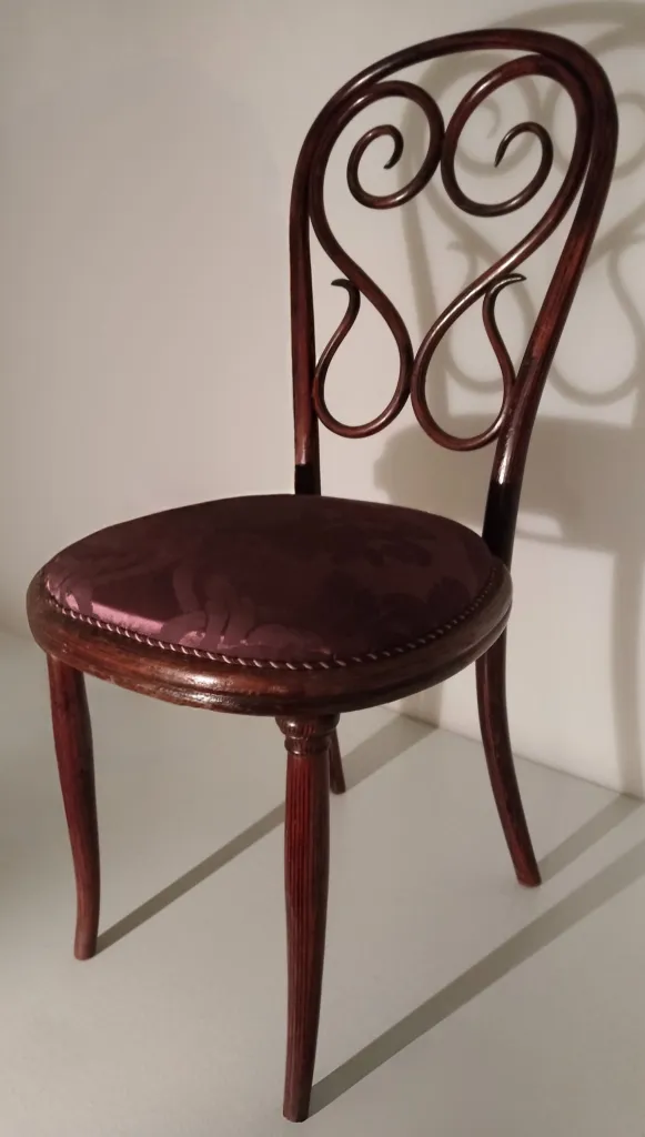 Side view of Thonet chair model No. 4 showing the curved decorative backrest and upholstered seat.