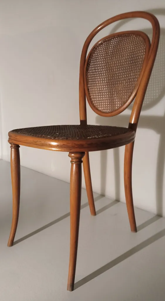 Side view of a Thonet bentwood chair, Model No. 7, showing curved backrest, cane seat, and two front legs with turned detailing.