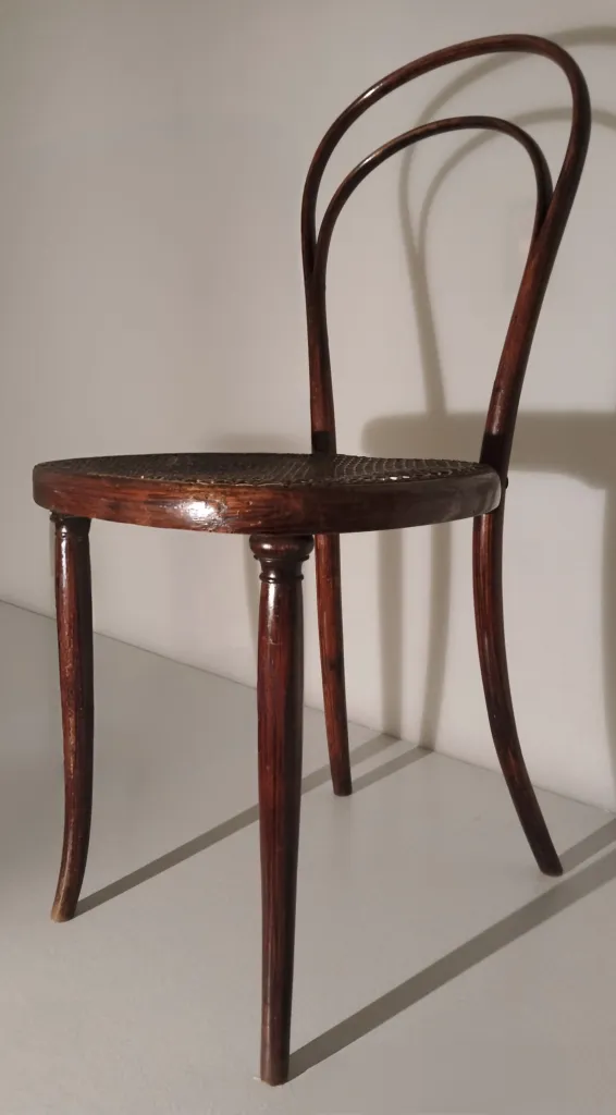Side view of Thonet bentwood chair Model No. 8, showing cane seat, turned front legs, and a double-arched backrest made from steam-bent wood.