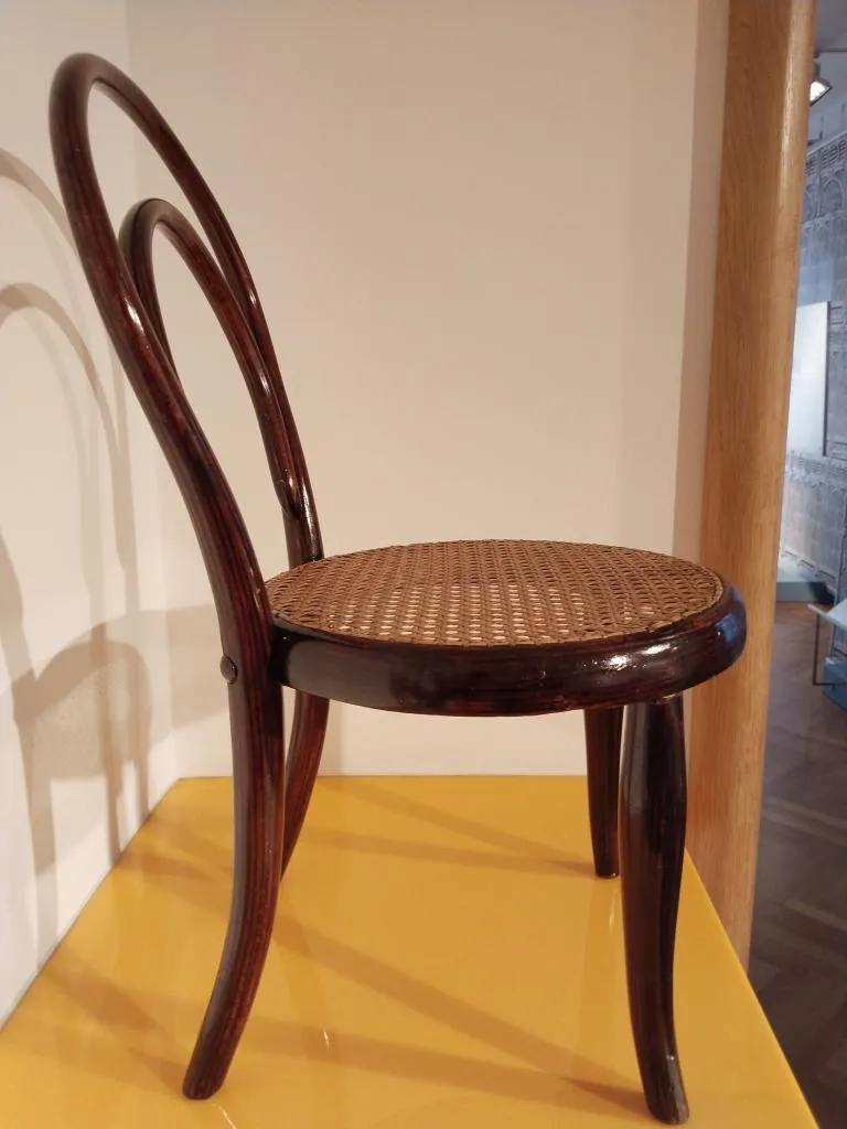 Seitenansicht des Thonet Kindersessels Nr. 1 mit geschwungenem Bugholzrücken und geflochtenem Sitz.