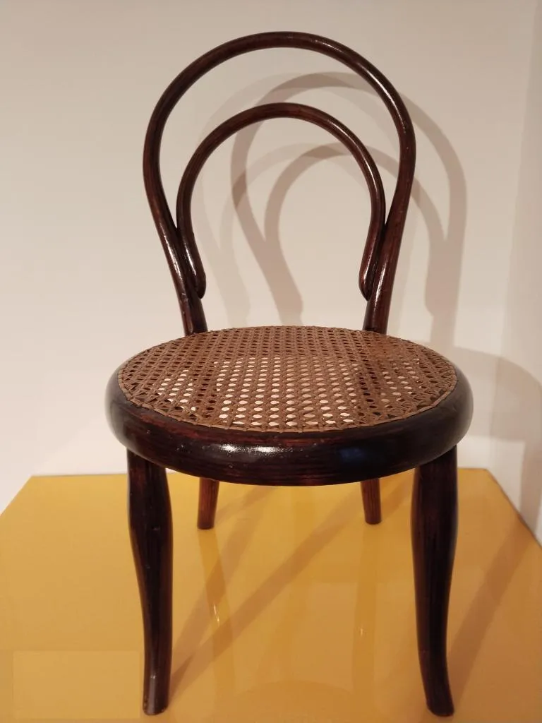 Fotografie des Thonet Kinderstuhls Nr. 14 mit Bugholzrahmen, rundem Rohrgeflecht-Sitz und elegant geschwungener Rückenlehne, angepasst an Kindergröße.