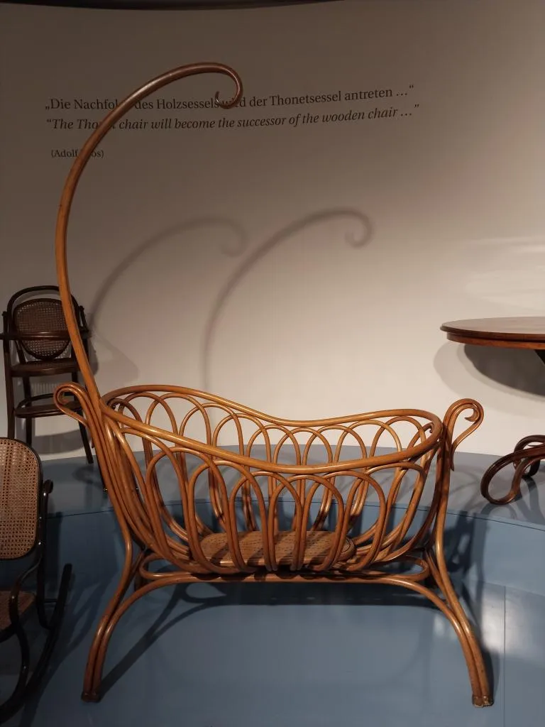Foto der Thonet Kinderschaukelwiege, Modell Nr. 1, Bugholzdesign mit hohem Bogen für Baldachin, um 1900 gefertigt, ausgestellt im Museum.