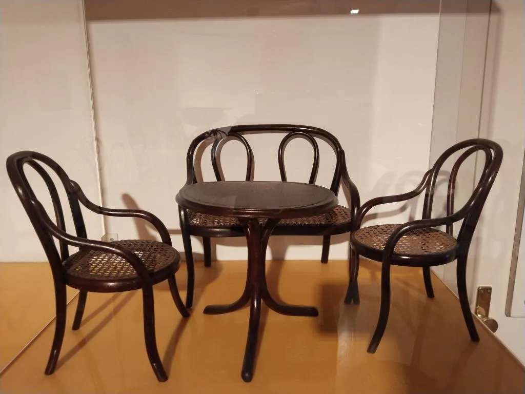 Thonet Puppenmöbel, Modell Nr. 1, um 1900, bestehend aus zwei kleinen Bugholzsesselchen, einer Bank und einem runden Tisch, im Museumsdisplay gezeigt.