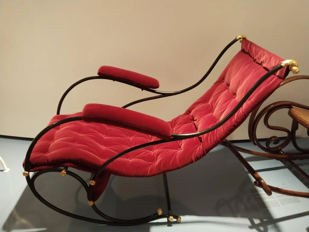 Thonet Schaukelsofa mit schwarzem Metallgestell, rotem Samtbezug, gepolsterten Armlehnen und vergoldeten Zierdetails, Modell und Herstellungsjahr unbekannt.